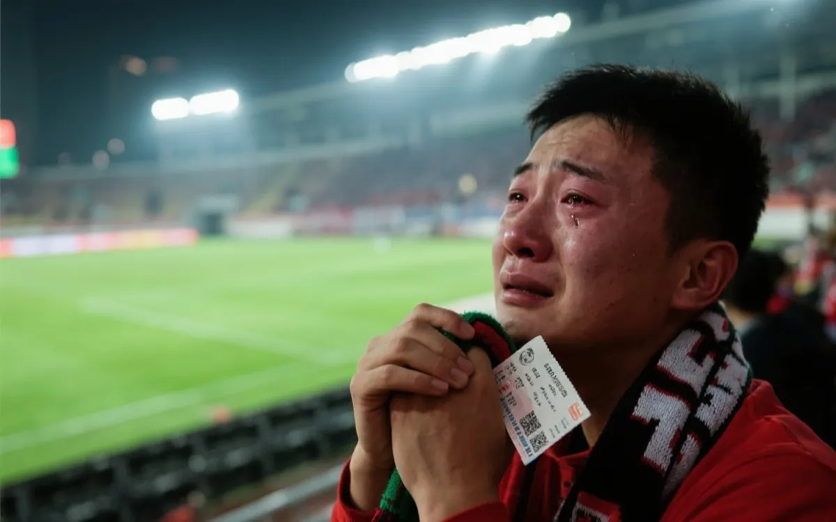 球场边缘近景：球迷紧握围巾与票根，眼眶湿润，背景是模糊的绿茵与灯光